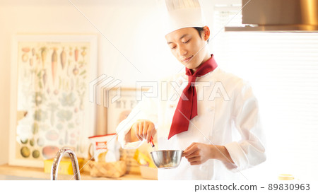 A young man standing in the kitchen with a scarf tie 89830963