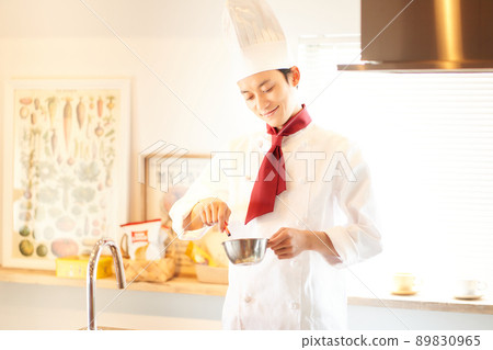 A young man standing in the kitchen with a scarf tie A young man standing in the kitchen with a scarf tie 89830965