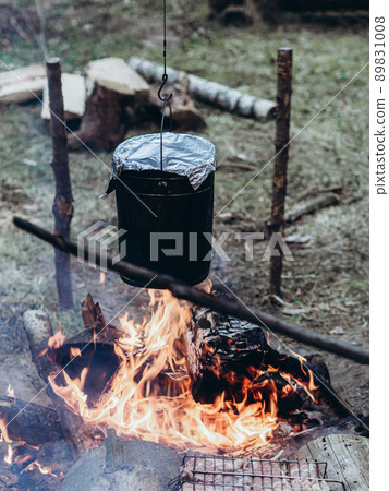 The kettle hangs over the fire. Cooking at the campsite. The kettle hangs over the fire. Cooking at the campsite. 89831008