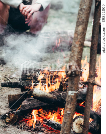 Unidentified male traveler warms his hands by the fire outdoors. 89831009
