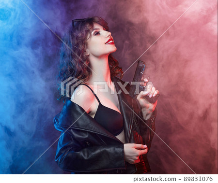beautiful young Caucasian girl with bright red lips poses with a gun. beautiful young Caucasian girl with bright red lips poses with a gun. 89831076