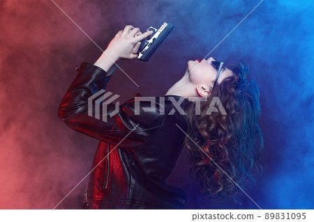 attractive young girl with sunglasses and red lips poses with a gun. attractive young girl with sunglasses and red lips poses with a gun. 89831095