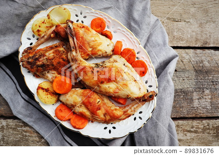 Roasted Rabbit Haunches in Pan with Stewed Vegetables on Rustic Wooden Table Surface 89831676