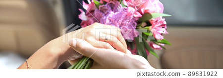 bride and groom holding the bride's bouquet ,sitting in the car 89831922