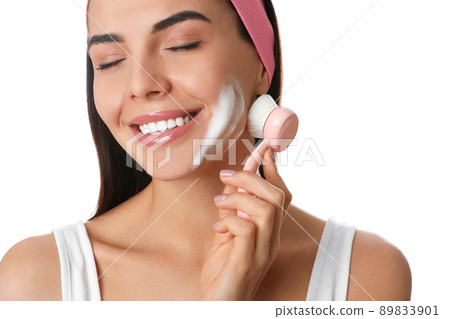 Young woman using facial cleansing brush on white background, closeup. Washing accessory Young woman using facial cleansing brush on white background, closeup. Washing accessory 89833901
