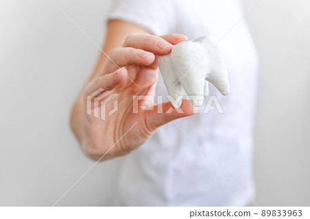 Health dental care concept. Woman hand holding white healthy tooth model isolated on white background. Teeth whitening, dental oral hygiene, teeth restoration, dentist day Health dental care concept. Woman hand holding white healthy tooth model isolated on white background. Teeth whitening, dental oral hygiene, teeth restoration, dentist day 89833963