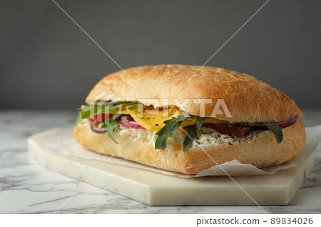 Delicious sandwich with fresh vegetables and cheese on white marble table 89834026