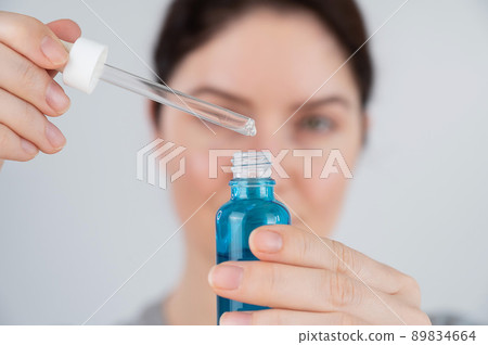 Caucasian woman uses blue anti-wrinkle face serum. Caucasian woman uses blue anti-wrinkle face serum. 89834664