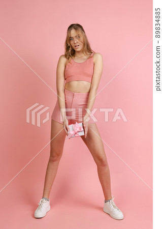 Monochrome portrait of young attractive woman in shorts and crop top isolated on pink background. Concept of beauty, art, fashion, youth, monochrome 89834885