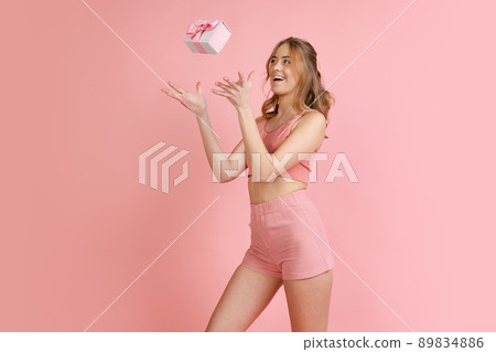 Monochrome portrait of young attractive woman in shorts and crop top isolated on pink background. Concept of beauty, art, fashion, youth Monochrome portrait of young attractive woman in shorts and crop top isolated on pink background. Concept of beauty, art, fashion, youth 89834886