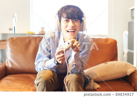A young man sitting on the couch at home and enjoying the game 89834917