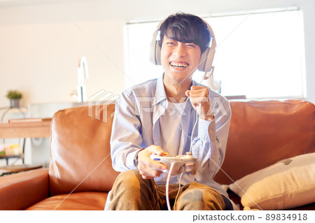 A young man sitting on the couch at home and enjoying the game 89834918