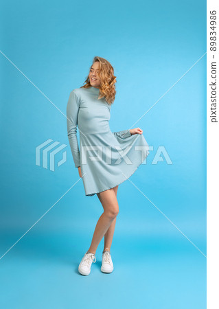 Studio shot of young sensual happy woman in blue dress isolated on blue background. Concept of beauty, art, fashion, youth, monochrome 89834986