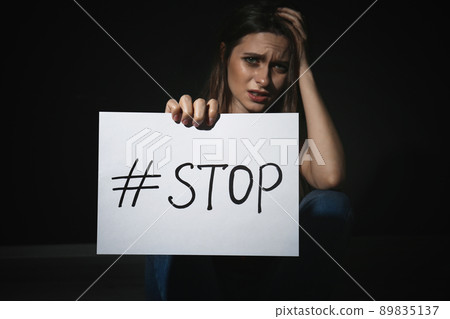 Crying young woman with hashtag STOP on black background. Domestic violence concept 89835137