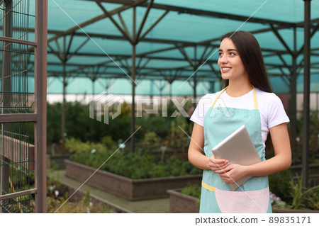 Female business owner with tablet in greenhouse. Space for text 89835171