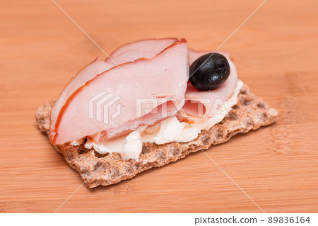 Whole Grain Crispbread with Ham, Cream Cheese and Olives 89836164