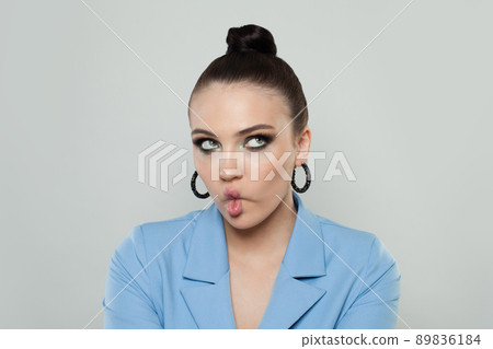 Cute young woman making funny face over white background Cute young woman making funny face over white background 89836184