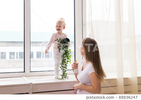 Happy child girl with cochlear implant having fun with her mother - hearing aid for deaf and innovative health technology concept Happy child girl with cochlear implant having fun with her mother - hearing aid for deaf and innovative health technology concept 89836247