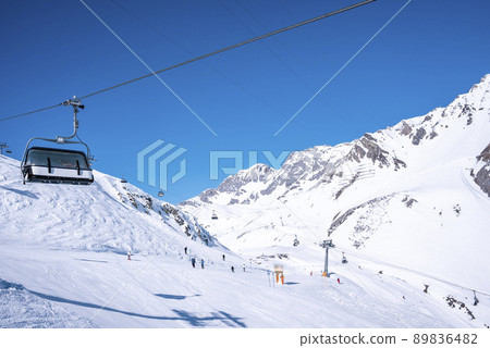 Ski lift traveling over snow covered mountain against clear blue sky Ski lift traveling over snow covered mountain against clear blue sky 89836482