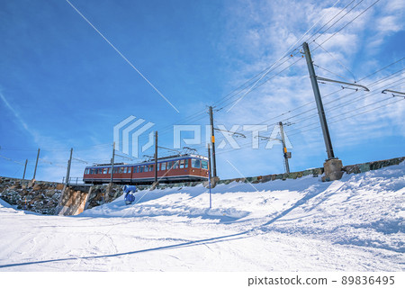Red train moving towards gornergrat station on mountain against blue sky 89836495