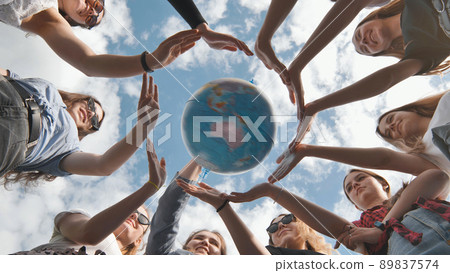 Earth conservation concept. 11 girls surround the rotating earth globe with their palms. 89837574