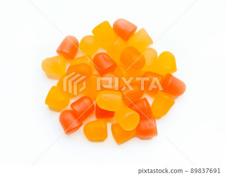 Close-up texture of orange and yellow multivitamin gummies in the form of bears on white background.  89837691