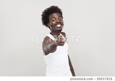 Hey you! Man in white t-shirt showing finger at camera. Studio shot. Gray background Hey you! Man in white t-shirt showing finger at camera. Studio shot. Gray background 89837828