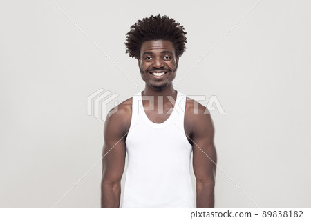 Happiness afro man looking at camera and toothy smiling. Studio shot. Gray background Happiness afro man looking at camera and toothy smiling. Studio shot. Gray background 89838182
