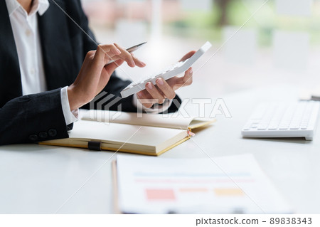 Asian Business Woman or Accountant do math and analyze with calculator and paperwork on desk, account, consult, audit and saving concept. Asian Business Woman or Accountant do math and analyze with calculator and paperwork on desk, account, consult, audit and saving concept. 89838343