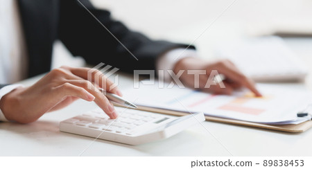 Asian Business Woman or Accountant do math and analyze with calculator and paperwork on desk, account, consult, audit and saving concept. 89838453