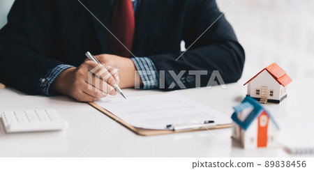 Close up of Businessman pointing and signing agreement for buying house. Bank manager concept. Close up of Businessman pointing and signing agreement for buying house. Bank manager concept. 89838456