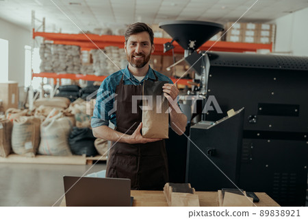 Business owner holding roasted coffee beans in paper bag in coffee factory Business owner holding roasted coffee beans in paper bag in coffee factory 89838921