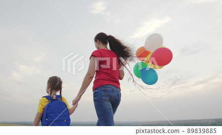 mother holds little child daughter with backpack against sky. happy family life. mom with kid girl walks along rural road park. teamwork. family adventures. travel naturechild hand parent 89839885
