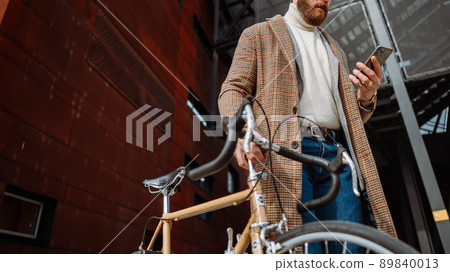 Midsection Detail of hand with phone. Businessman holding mobile phone. On the way to work with bicycle 89840013