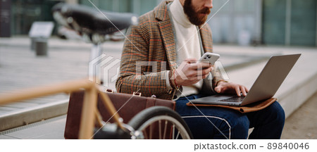 Cover photo. Midsection of man sitting outside with laptop and mobile. Online call. Working outside 89840046
