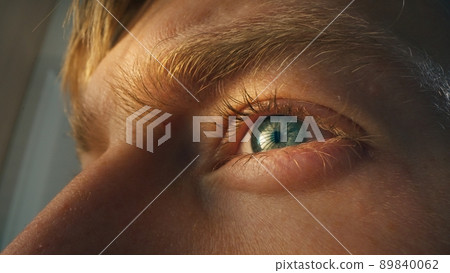 Detail shot of human blue eye. Young man working on computer. Concentrated look. 89840062