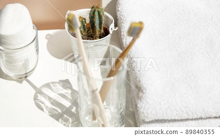 Corner of the bathroom. in the photo toothbrushes in a glass on a background of white cotton towels. 89840355