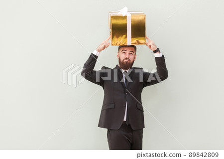 Dreaming or idea concept. Thoughtful businessman dreams and holding box on a head. Indoor shot 89842809