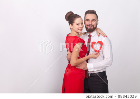 Young couple celebrate valentines day, hugging and toothy smile. Indoor, studio shot, isolated on gray background Young couple celebrate valentines day, hugging and toothy smile. Indoor, studio shot, isolated on gray background 89843029