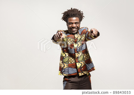 Emotion african man, toothy smiling pointing fingers at camera. Indoor, isolated on gray background Emotion african man, toothy smiling pointing fingers at camera. Indoor, isolated on gray background 89843033