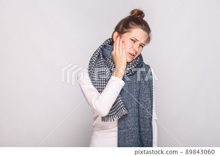 Sick woman holding hand her cheeh, have a toothache. Studio shot, gray wall Sick woman holding hand her cheeh, have a toothache. Studio shot, gray wall 89843060