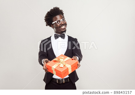 Romantic african businessman showing gift box for valentines day. Studio shot. Romantic african businessman showing gift box for valentines day. Studio shot. 89843157