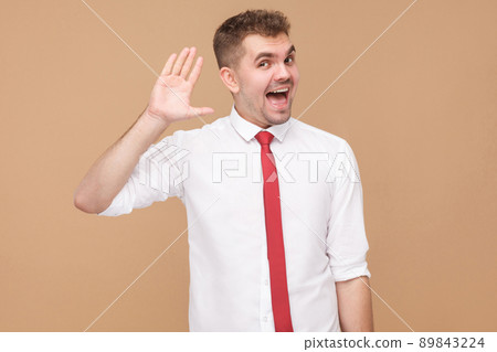 Happy businessman showing hi, hello sign. Business people concept, good and bad emotion and feelings. Studio shot, isolated on light brown background Happy businessman showing hi, hello sign. Business people concept, good and bad emotion and feelings. Studio shot, isolated on light brown background 89843224