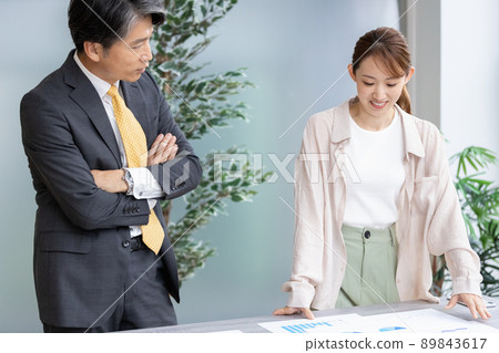 Two business people holding a standing meeting Two business people holding a standing meeting 89843617