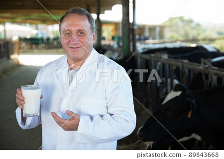 Smiling male farmer in white robe with milk 89843668