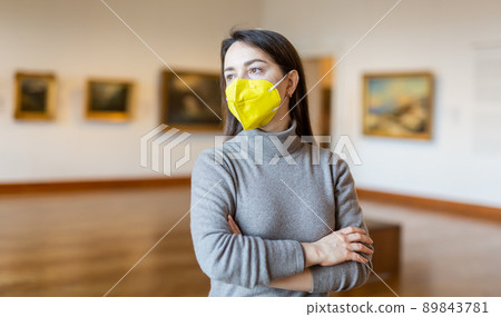 Woman tourist in protective mask admiring artworks at paintings exposition Woman tourist in protective mask admiring artworks at paintings exposition 89843781