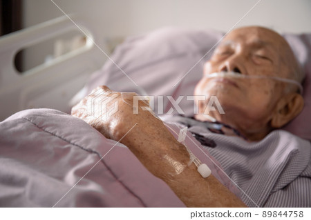 Normal Saline Solution or NSS plug socket for injector is plugged in on the hand of old patient close up with copyspace. Medication service and healthcare in elder people. 89844758