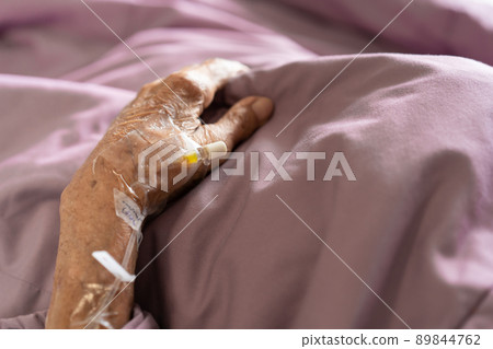 Normal Saline Solution or NSS plug socket for injector is plugged in on the hand of old patient close up with copyspace. Medication service and healthcare in elder people. 89844762