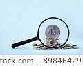 Bitcoin through a magnifying glass against the background of the coin. Stock Market Concept. Exchange bitcoin on cash for a money. Cryptocurrency. Digital modern method of payment 89846429