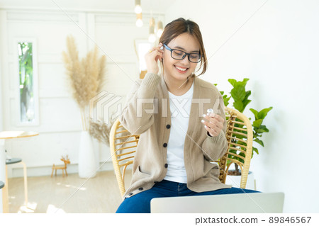 Young woman using wireless headphone listening to music. 89846567